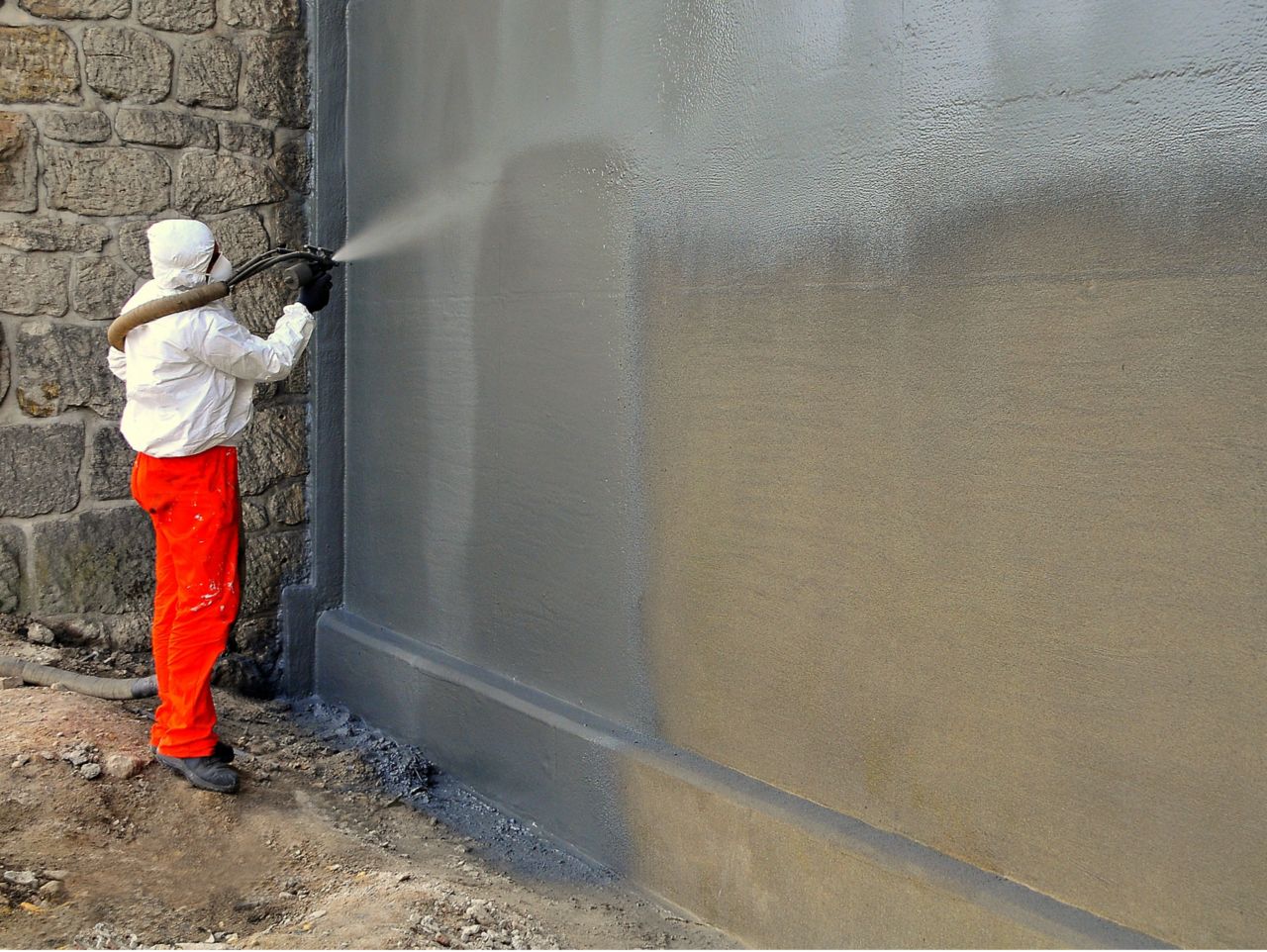 Man spraying liquid-applied membrane on a wall