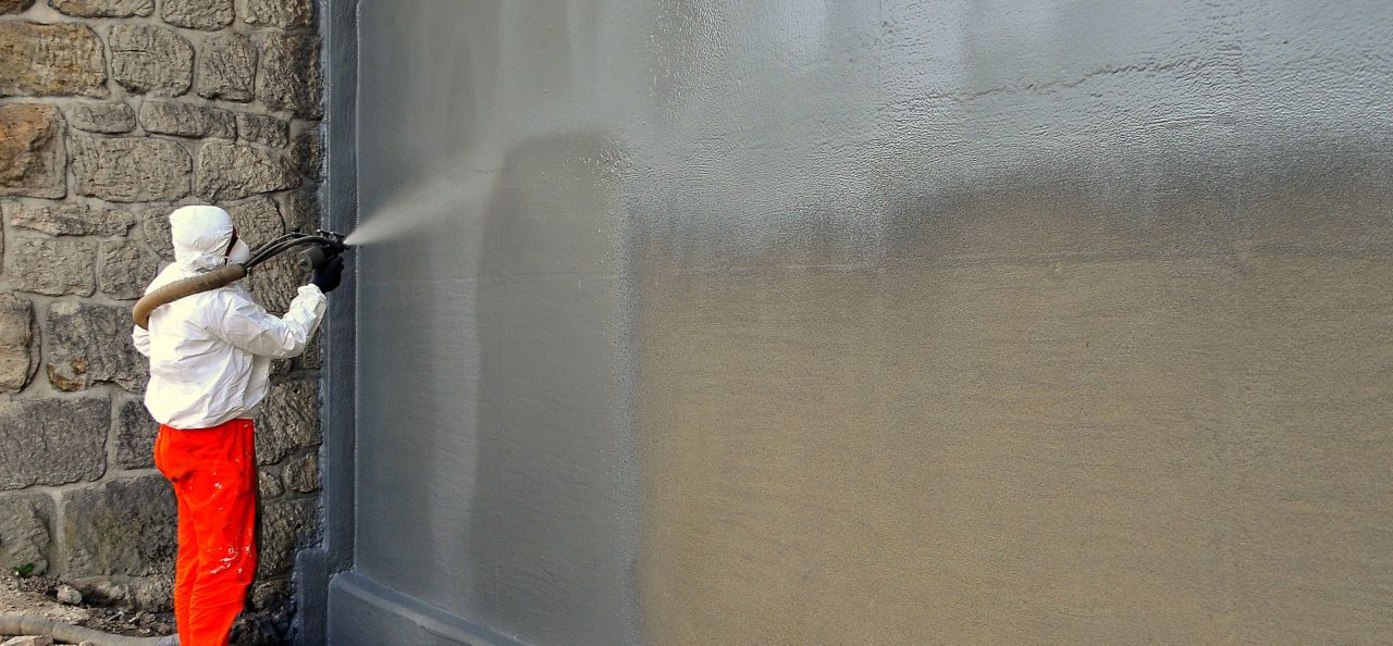 Man spraying liquid-applied membrane on a wall