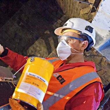 建筑工人在铸铁梁上涂环氧胶粘剂