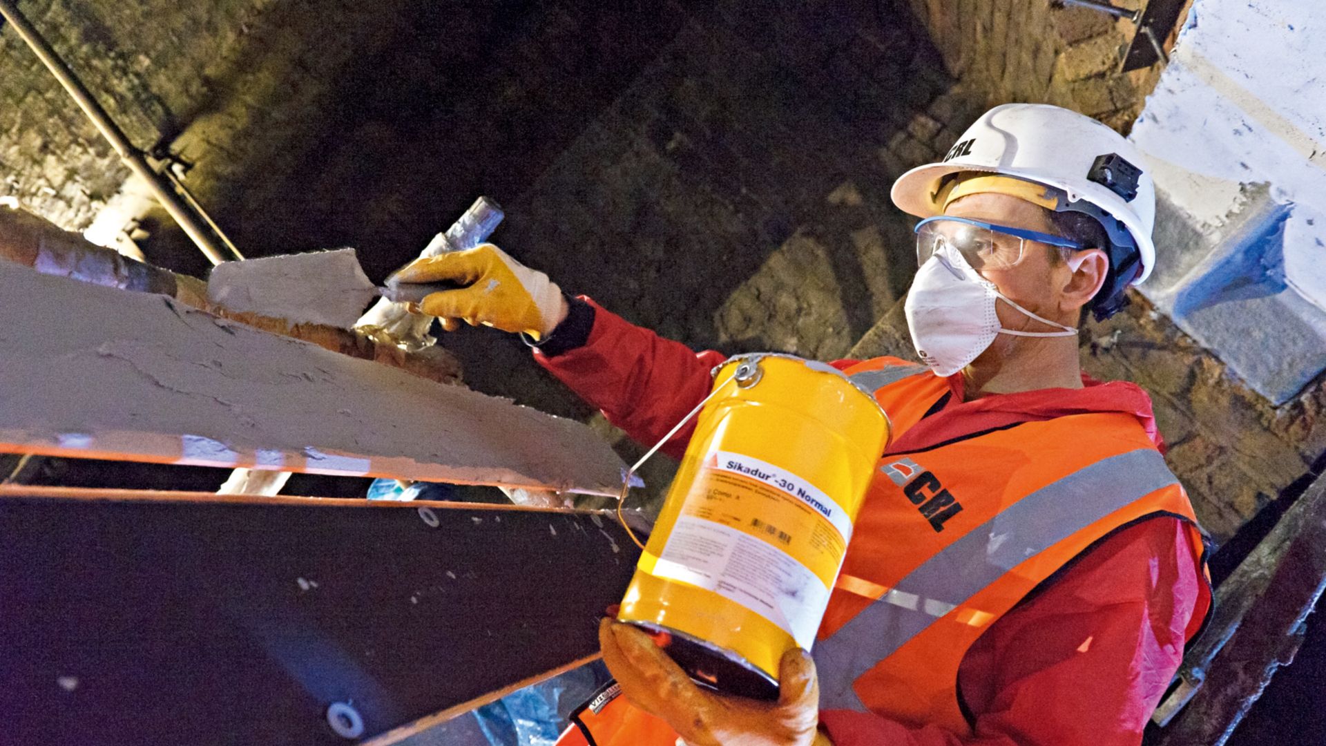 Construction worker applies epoxy adhesive on cast-iron beams