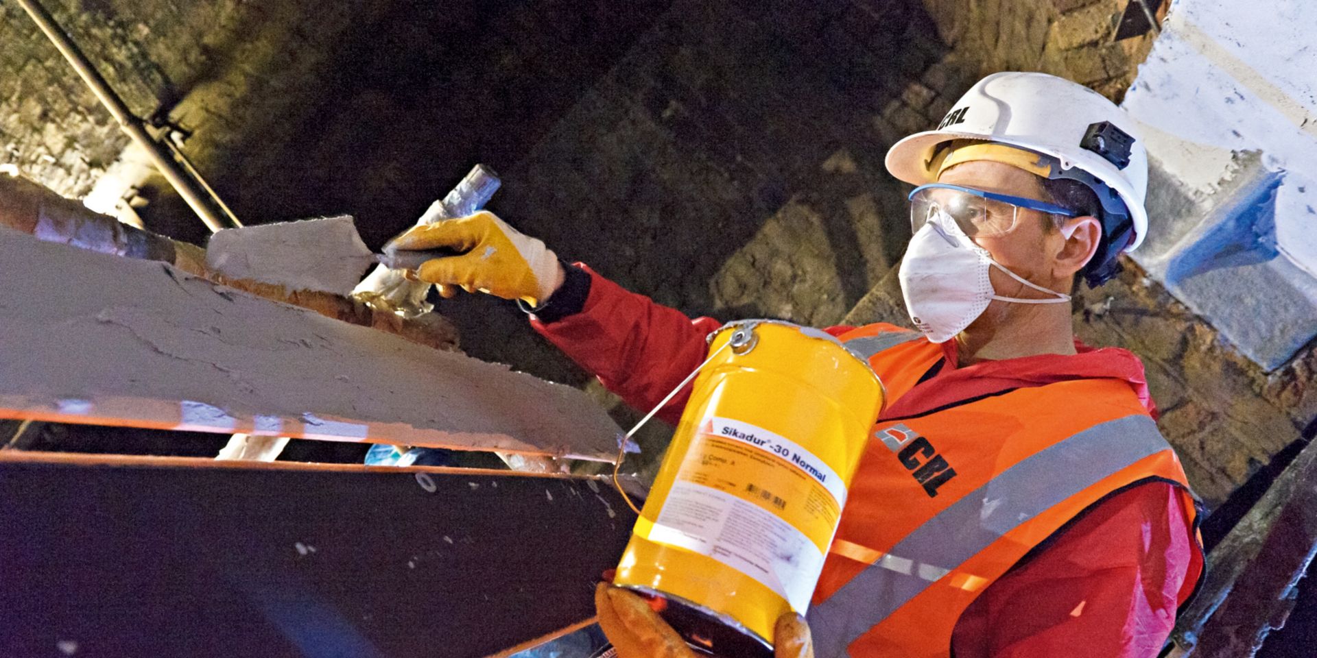 Construction worker applies epoxy adhesive on cast-iron beams