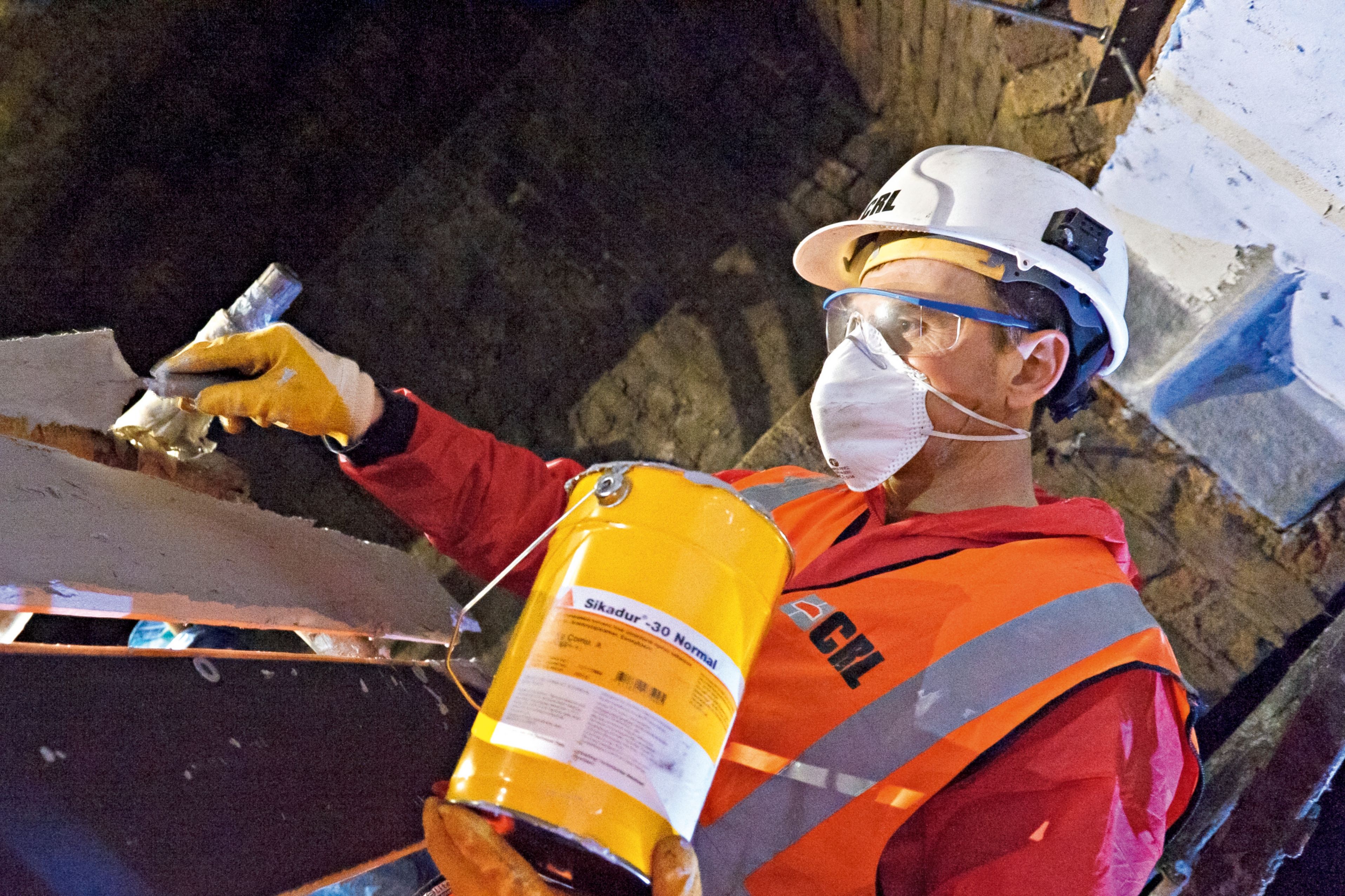 建筑工人在铸铁梁上涂环氧胶粘剂