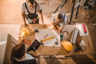 工人人聚集在与片剂和蓝图的表附近