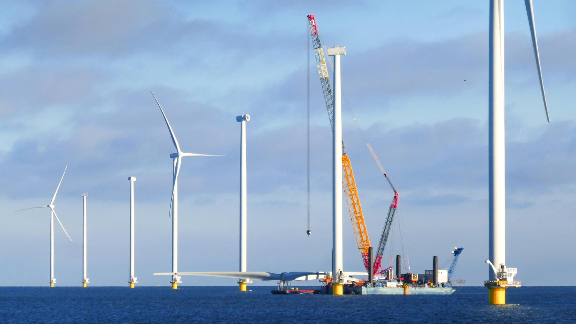 建造海上风电场-荷兰海上风力涡轮机(markermeer)。起重机船正在准备吊起风力发电机的转子。阳光明媚的天气和大气的心情。