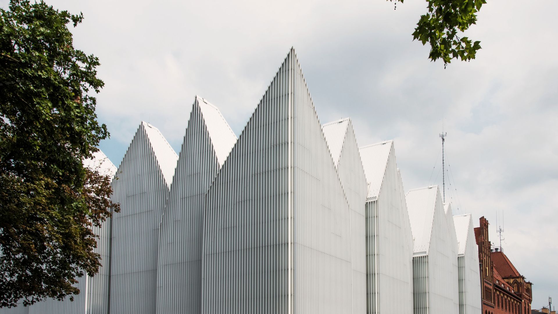 White facade of Szczecin Philharmonic Hall contrasting with old red buildings