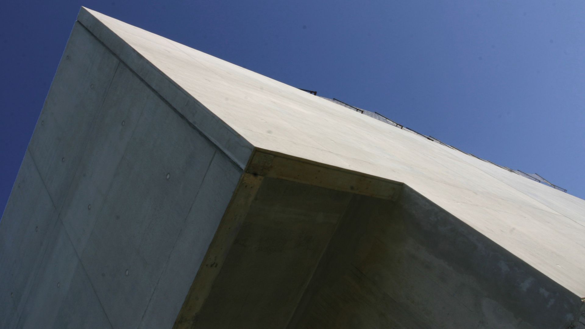 Rigid bonding of prefabricated concrete facade panels to building with architectural smooth concrete and blue sky