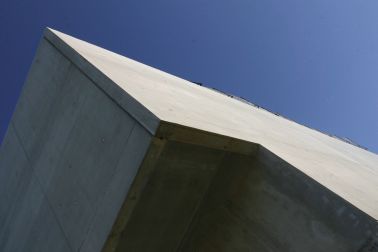 Rigid bonding of prefabricated concrete facade panels to building with architectural smooth concrete and blue sky