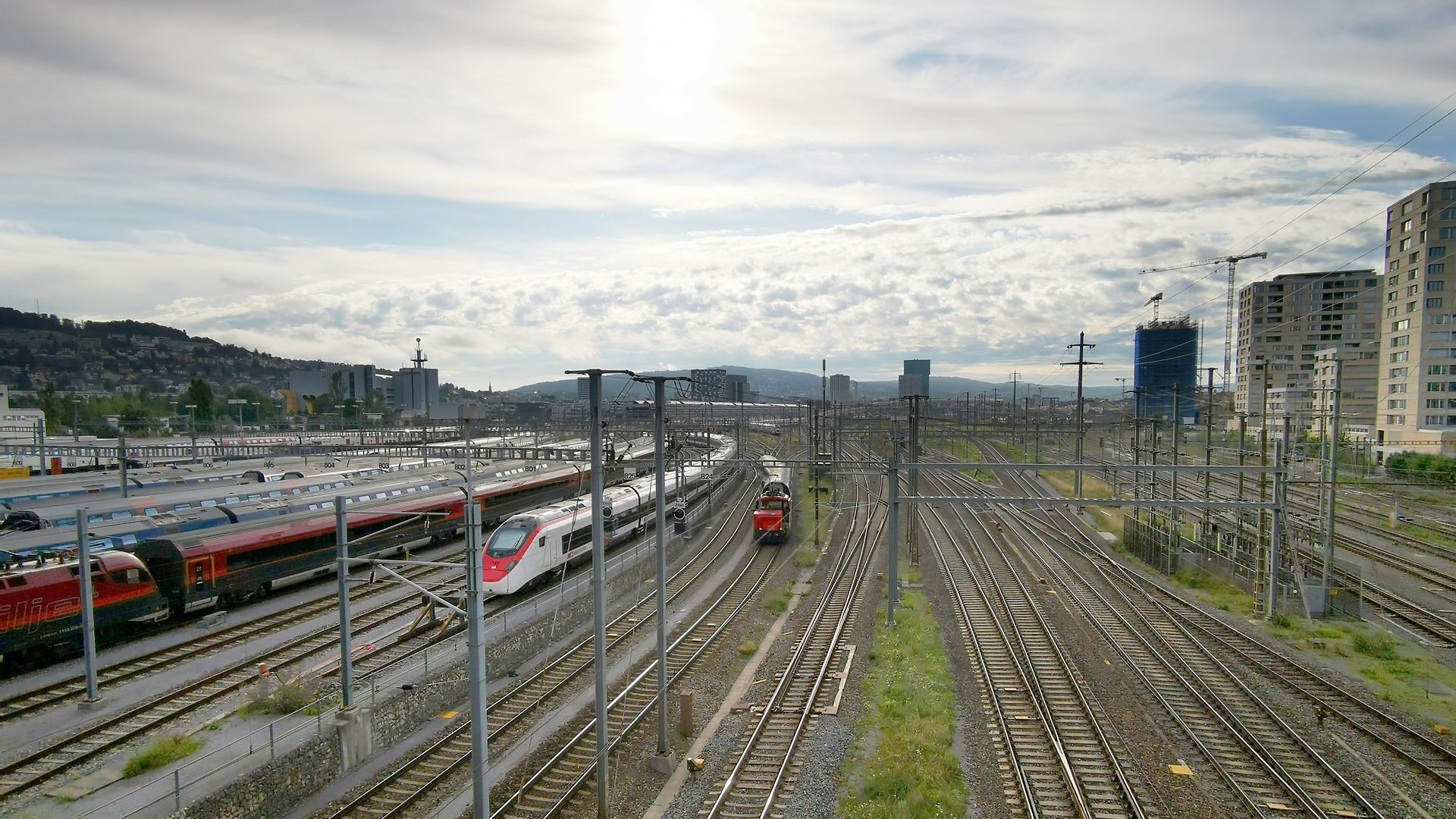 Trains on rail tracks in Zurich with sun in sky