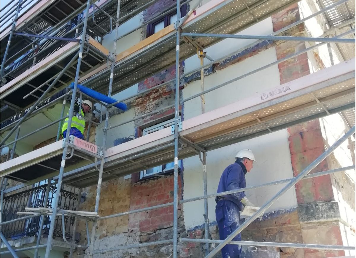 Construction workers applying renovation mortar on wall