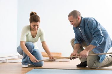 2 people applying a sandwich panel SikaMelt bonded wood floor to the house floor