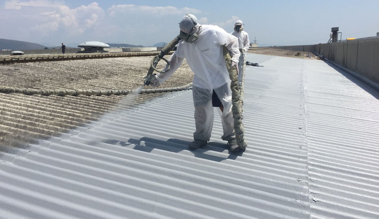 Applicators applying liquid applied membrane to corrugated metal roof in protective clothing