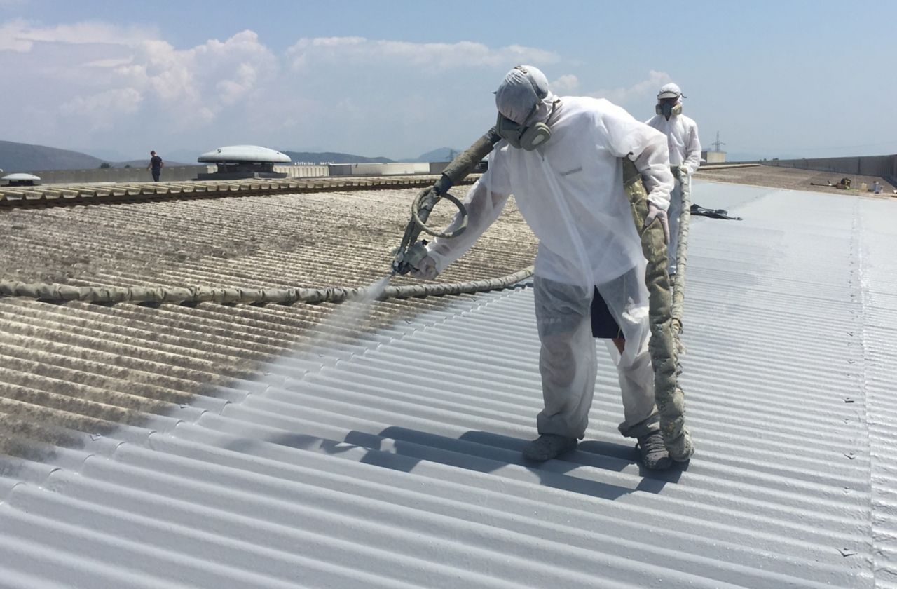 Applicators applying liquid applied membrane to corrugated metal roof in protective clothing