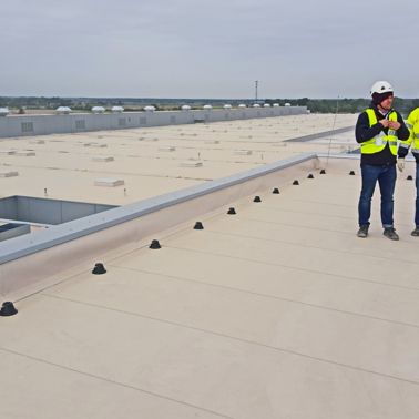 Two construction workers standing on Sarnafil waterproofing membrane on roof of Volkswagen Plant