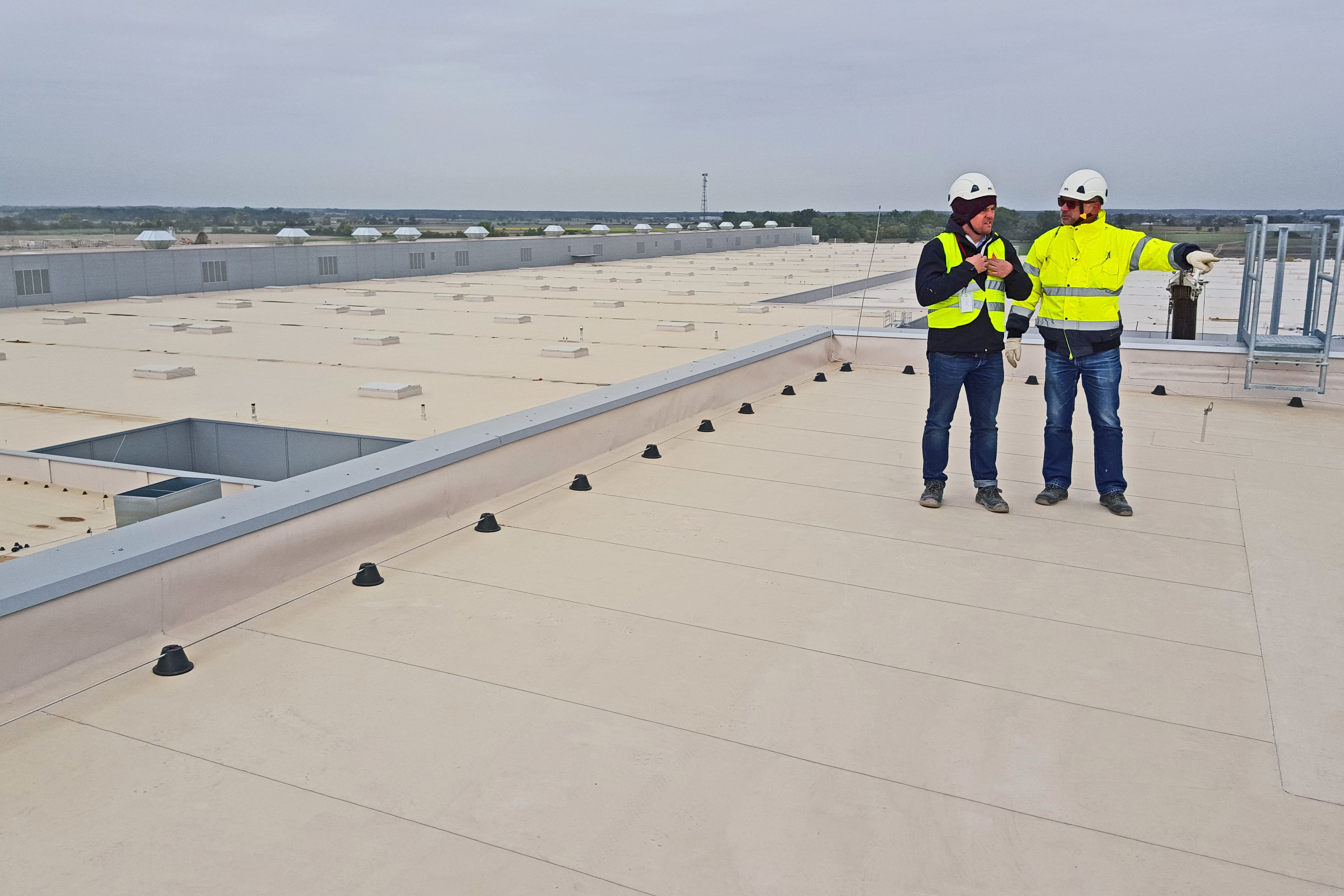 Two construction workers standing on Sarnafil waterproofing membrane on roof of Volkswagen Plant