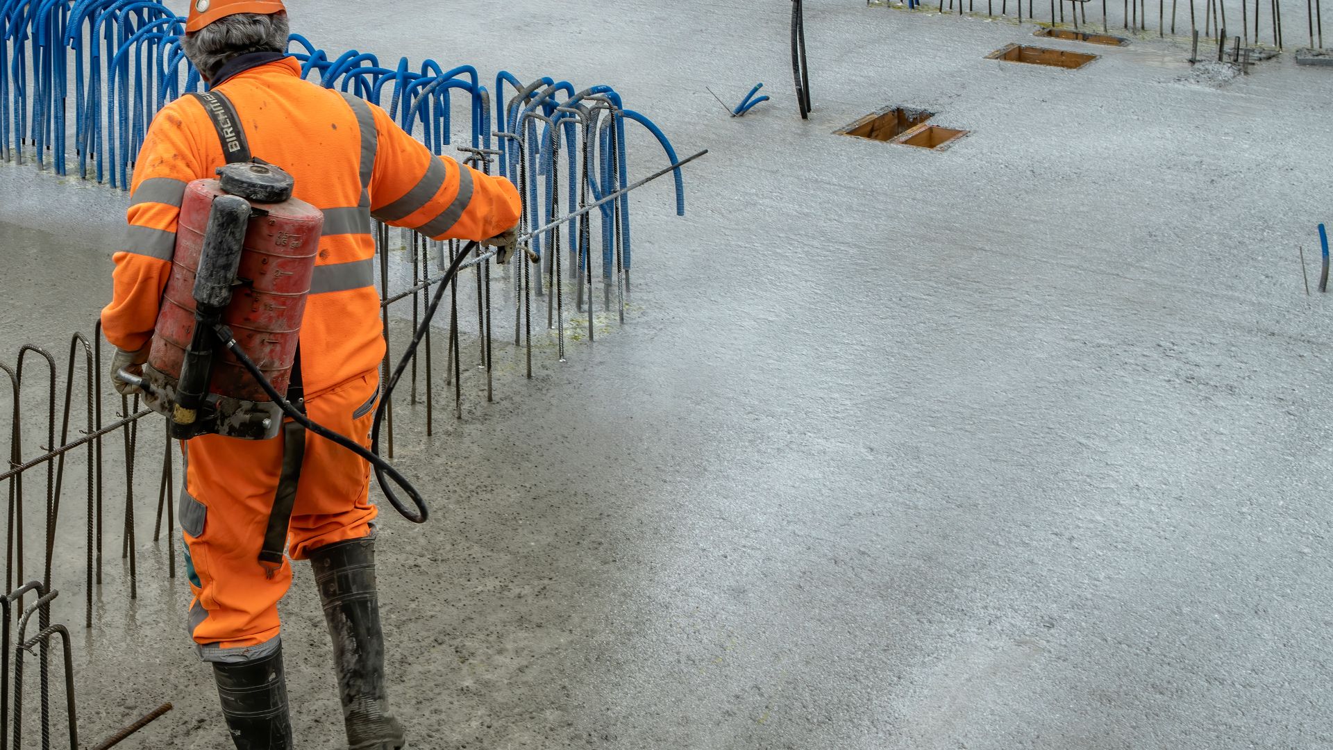 Man applying Sika® Antisol® curing compound on concrete on construction site with reinforcement