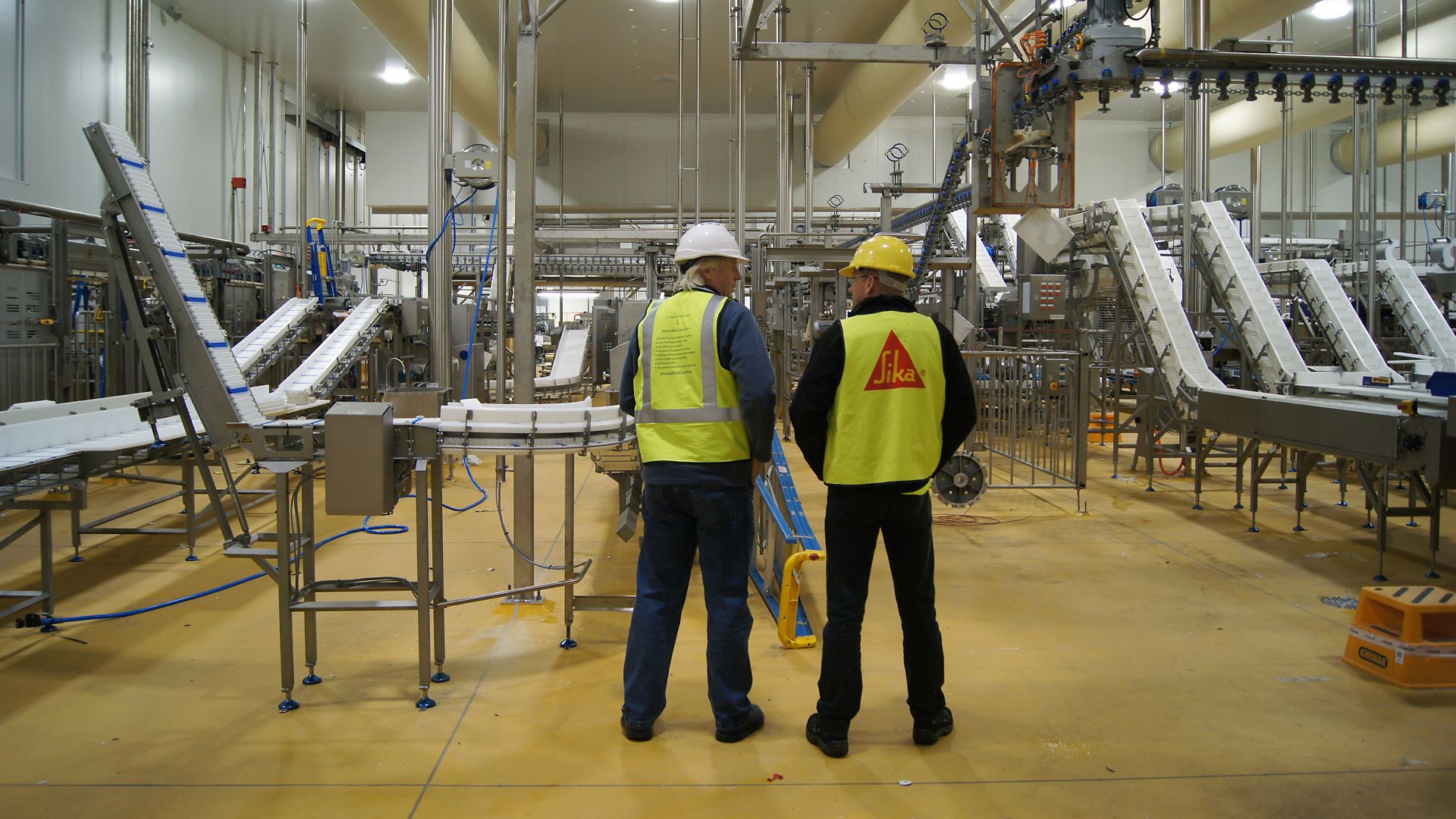 Sika man and owner food beverage factory standing talking side by side with Sika yellow floor Sikafloor® PurCem®