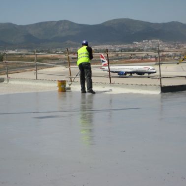 Worker applying waterproofing LAM system at the Barcelona El Prat Airport
