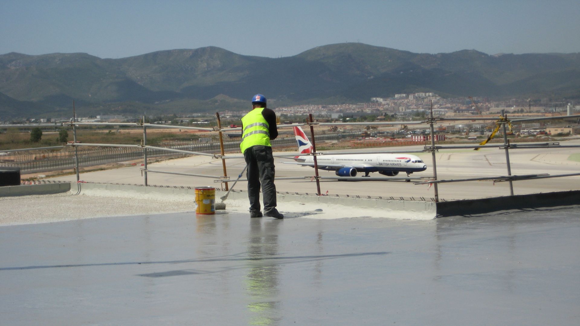 Worker applying waterproofing LAM system at the Barcelona El Prat Airport