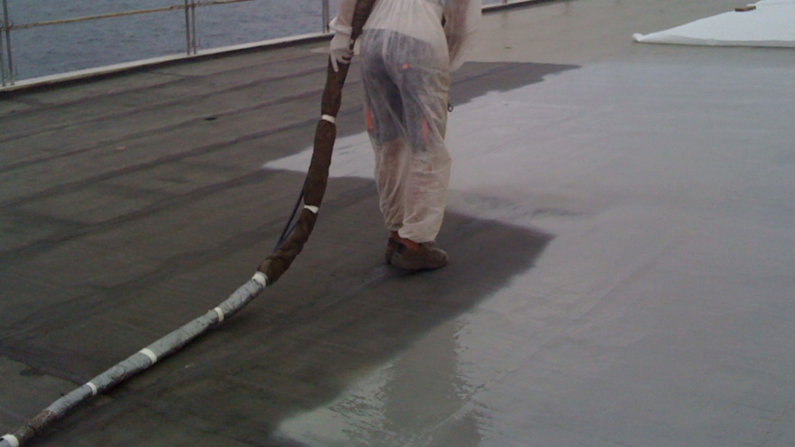 Worker applying waterproofing LAM system at the Barcelona El Prat Airport