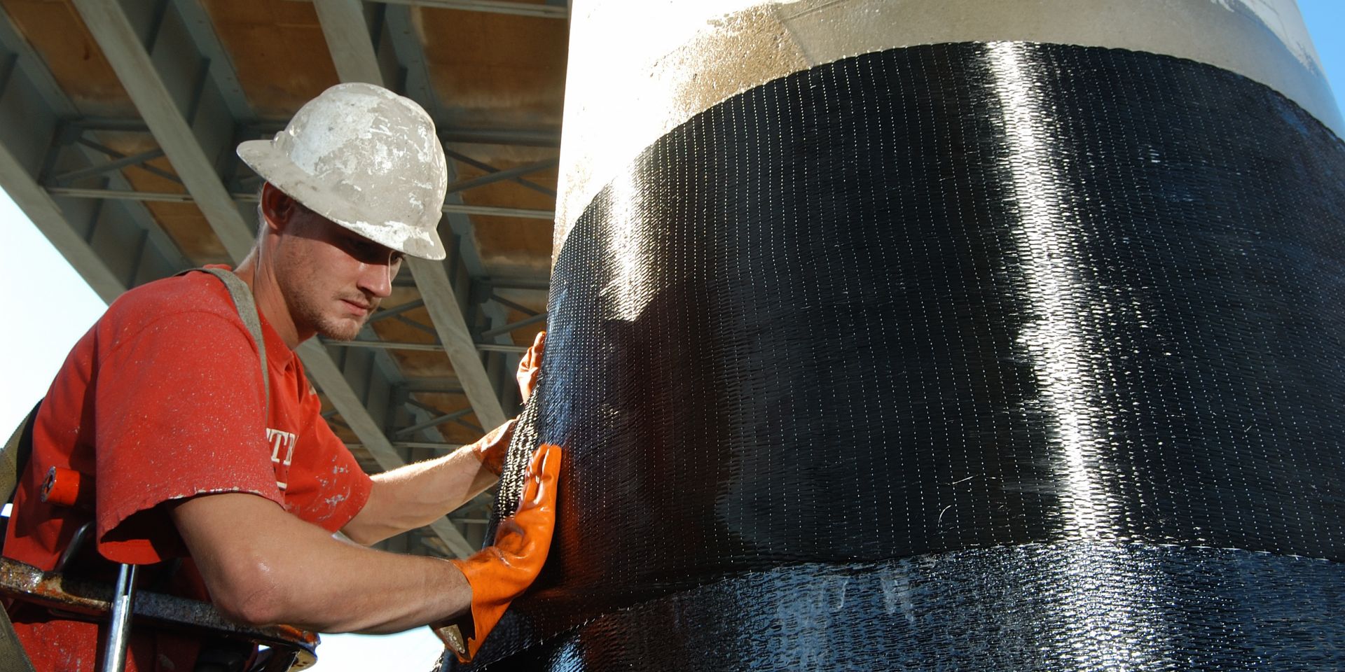 Men applying Sika CarboDur carbon fiber plates for structural strengthening