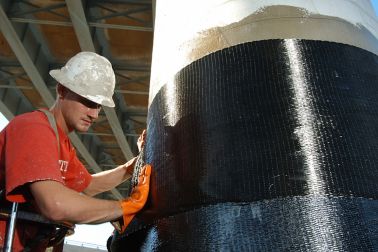 Men applying Sika CarboDur carbon fiber plates for structural strengthening