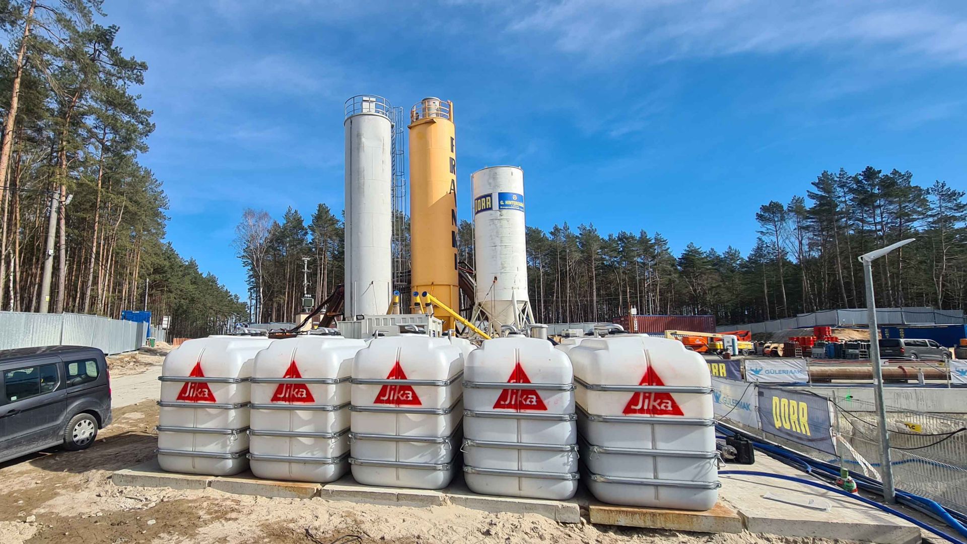 Sika admixture containers on site with blue sky and forest at Swina River crossing in Poland tunnel project