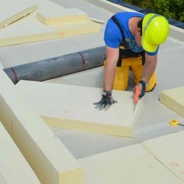 Man cutting installing thermal insulation on a roof