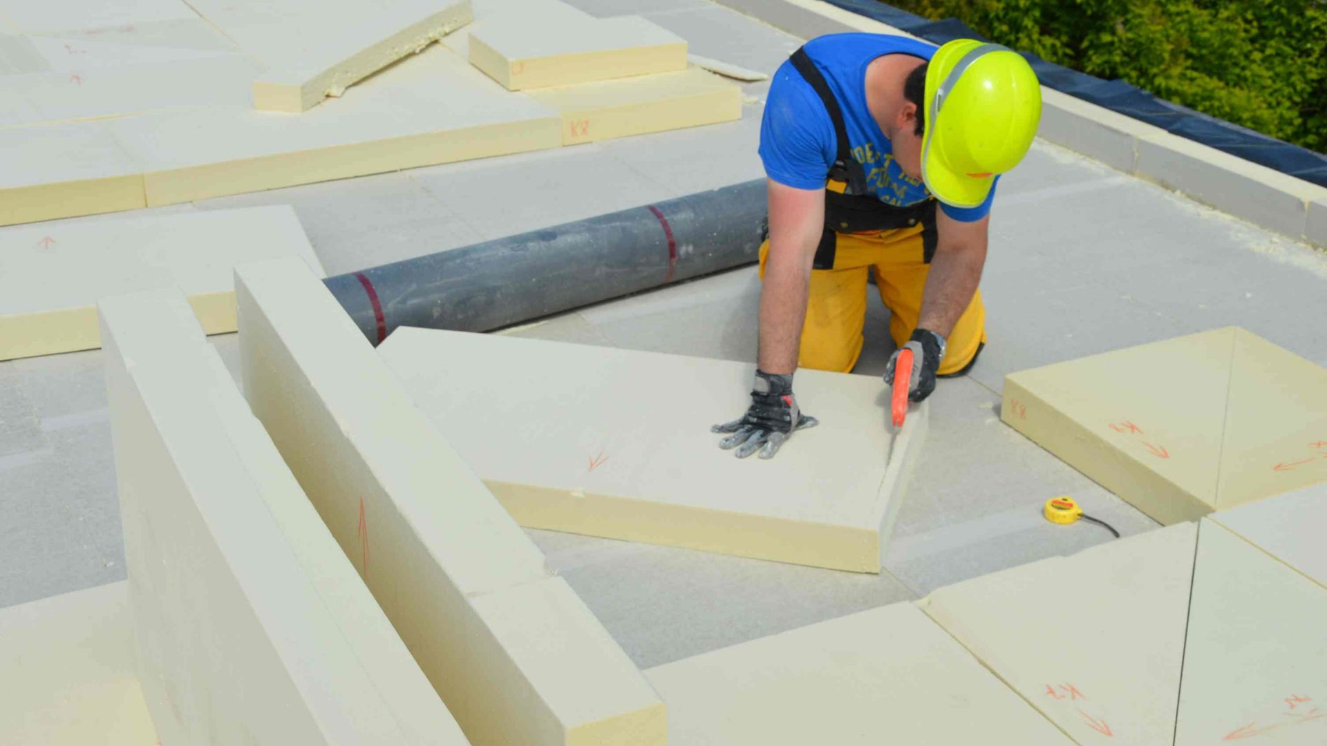 Man cutting installing thermal insulation on a roof