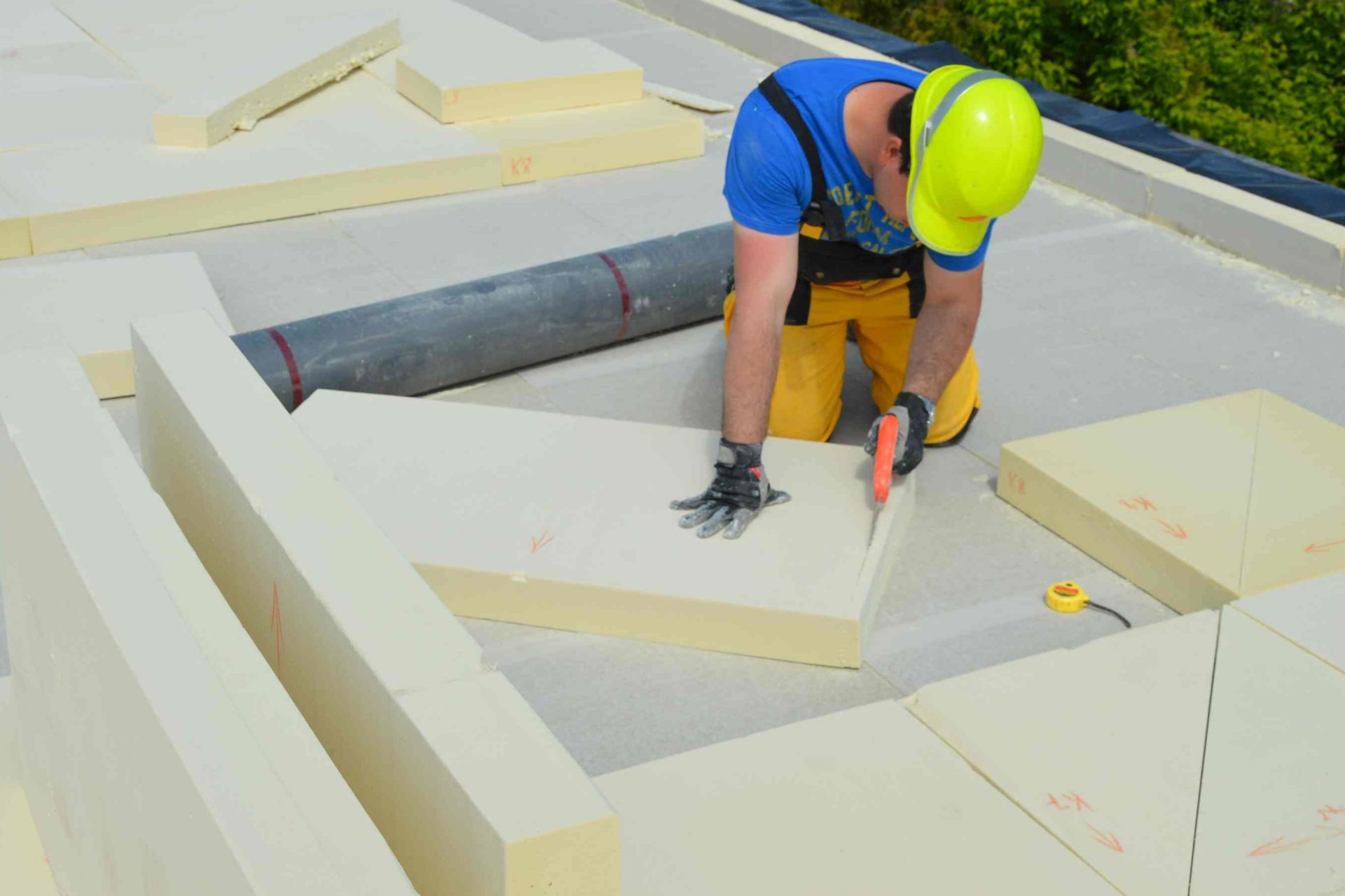 Man cutting installing thermal insulation on a roof