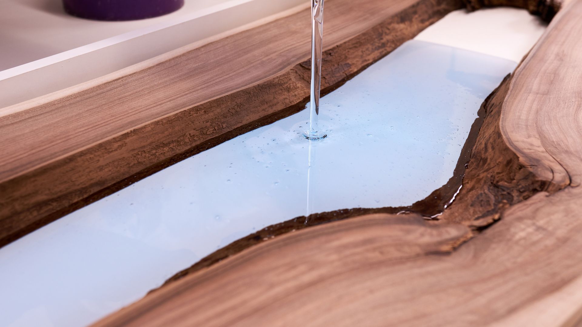Process making of a craft resin and wood table. Liquid epoxy is poured into a mold with wooden blanks. closeup
