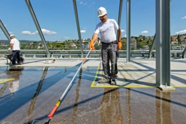 Man applying waterproof coating to concrete floor at Limmat building in Zurich