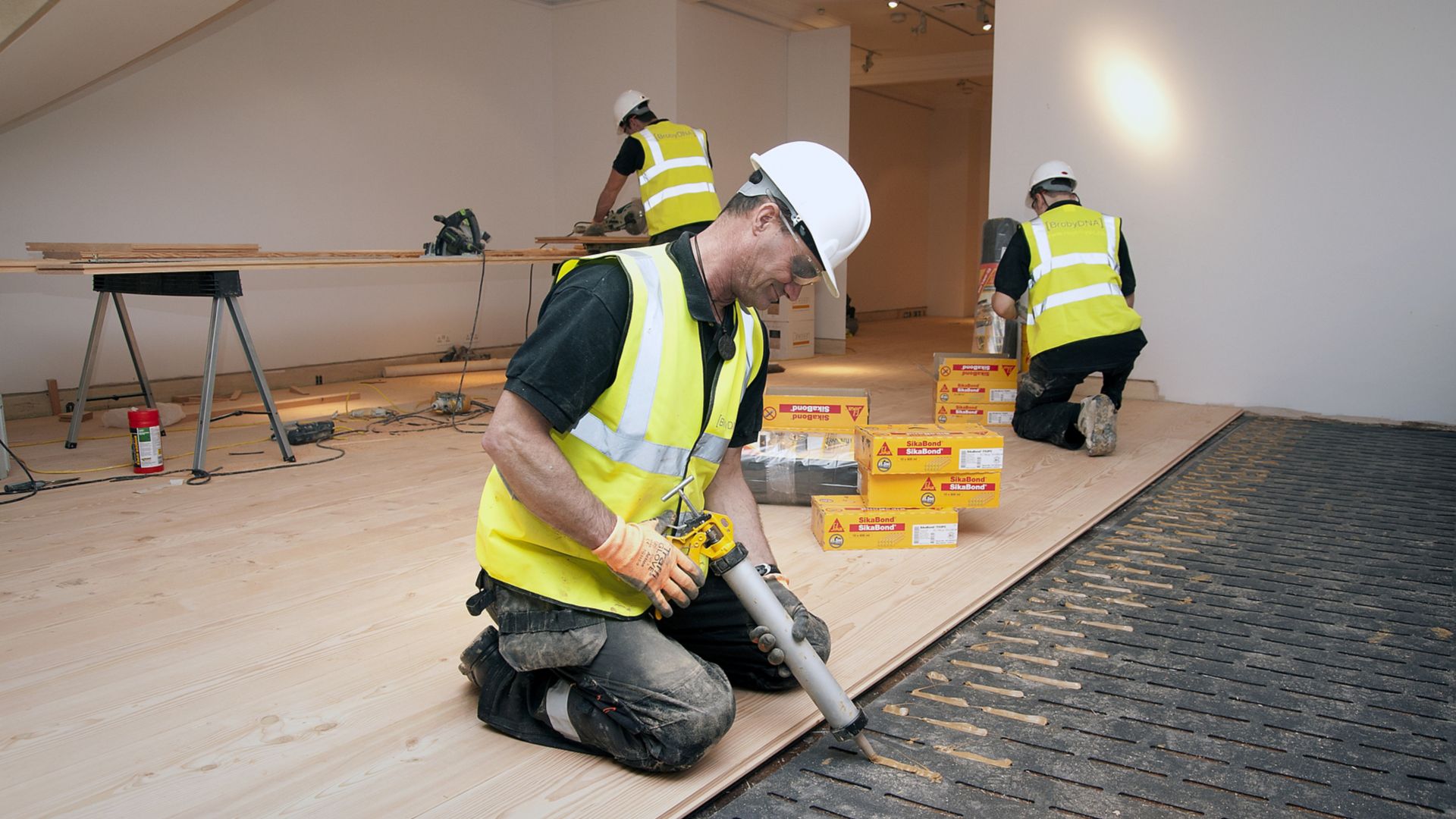 Workers applying wood floor adhesives in a residential building