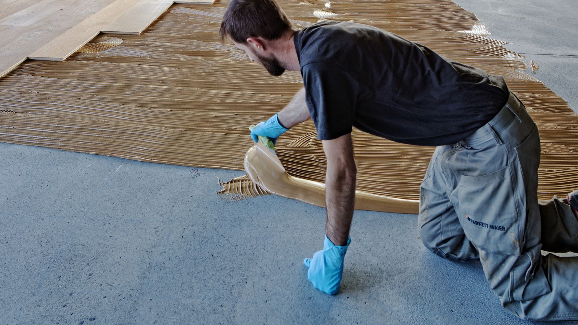 Workers applying wood floor adhesives