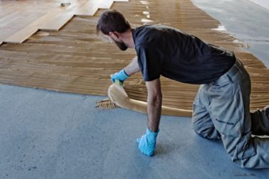 Workers applying wood floor adhesives