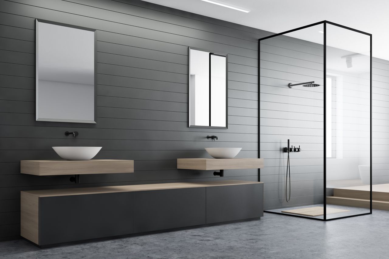 Corner of modern bathroom with gray walls, concrete floor, double sink with mirrors, gray cabinet and shower with glass walls. 3d rendering