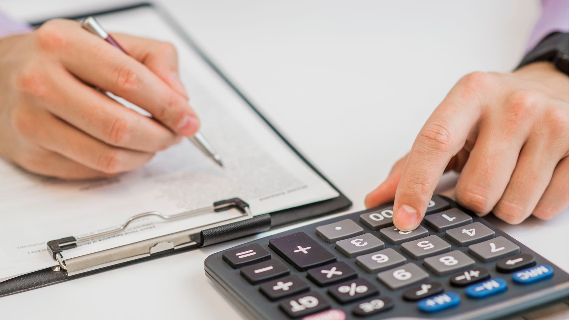 Close-up Of Businessman Calculating Invoices Using Calculator