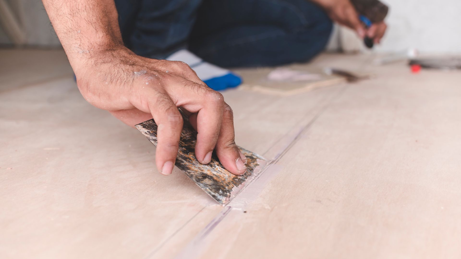 A carpenter filling gaps in wood floors. At the attic, home renovation, restoration or construction.