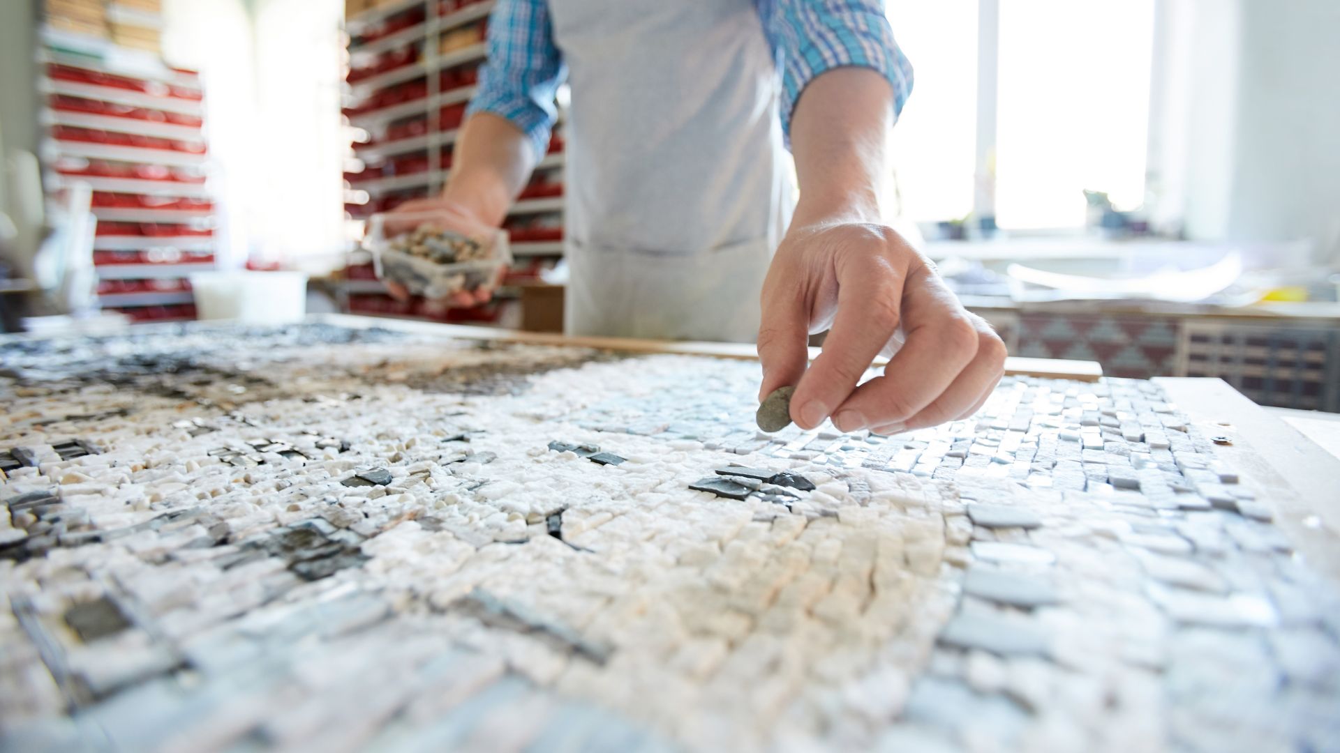 Close up shot of unrecognizable artist laying out tiles while creating mosaic in workshop, copy space