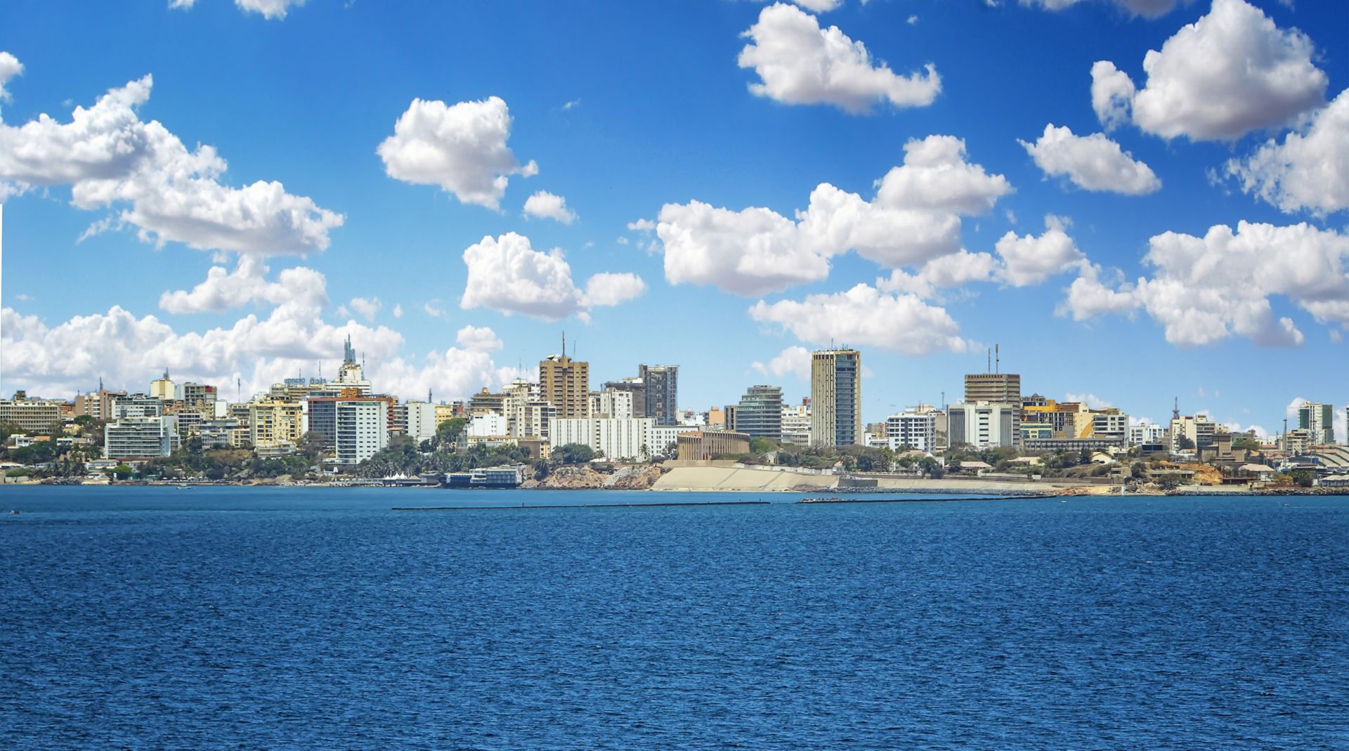 View of the Senegal capital of Dakar, Africa. It is a city panorama taken from a boat. There are large modern buildings and a blue sky with clouds. It's summer.