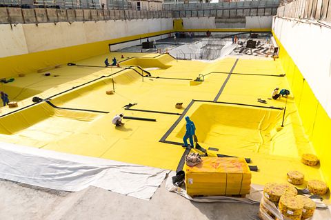    Construction workers applying a below-grade waterproofing membrane	 