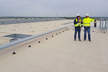 Two construction workers standing on Sarnafil waterproofing membrane on roof of Volkswagen Plant