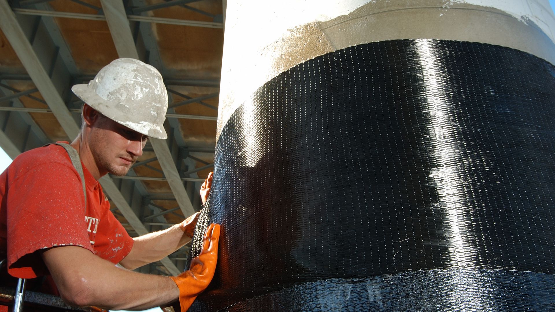 Men applying Sika CarboDur carbon fiber plates for structural strengthening