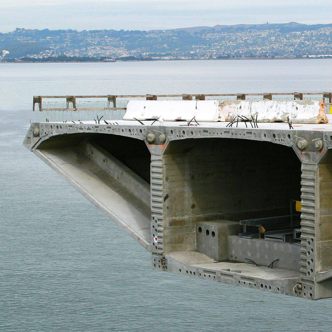 Bridge under construction over water with mountains in the background