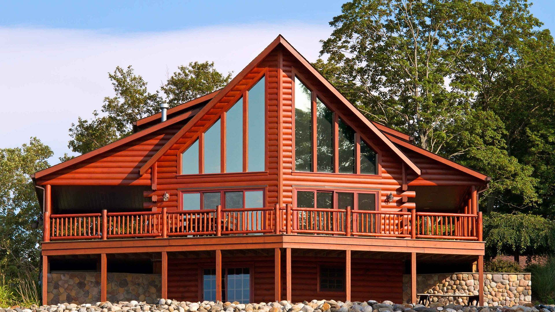 log home with trees in background; log home with large deck and A-frame windows