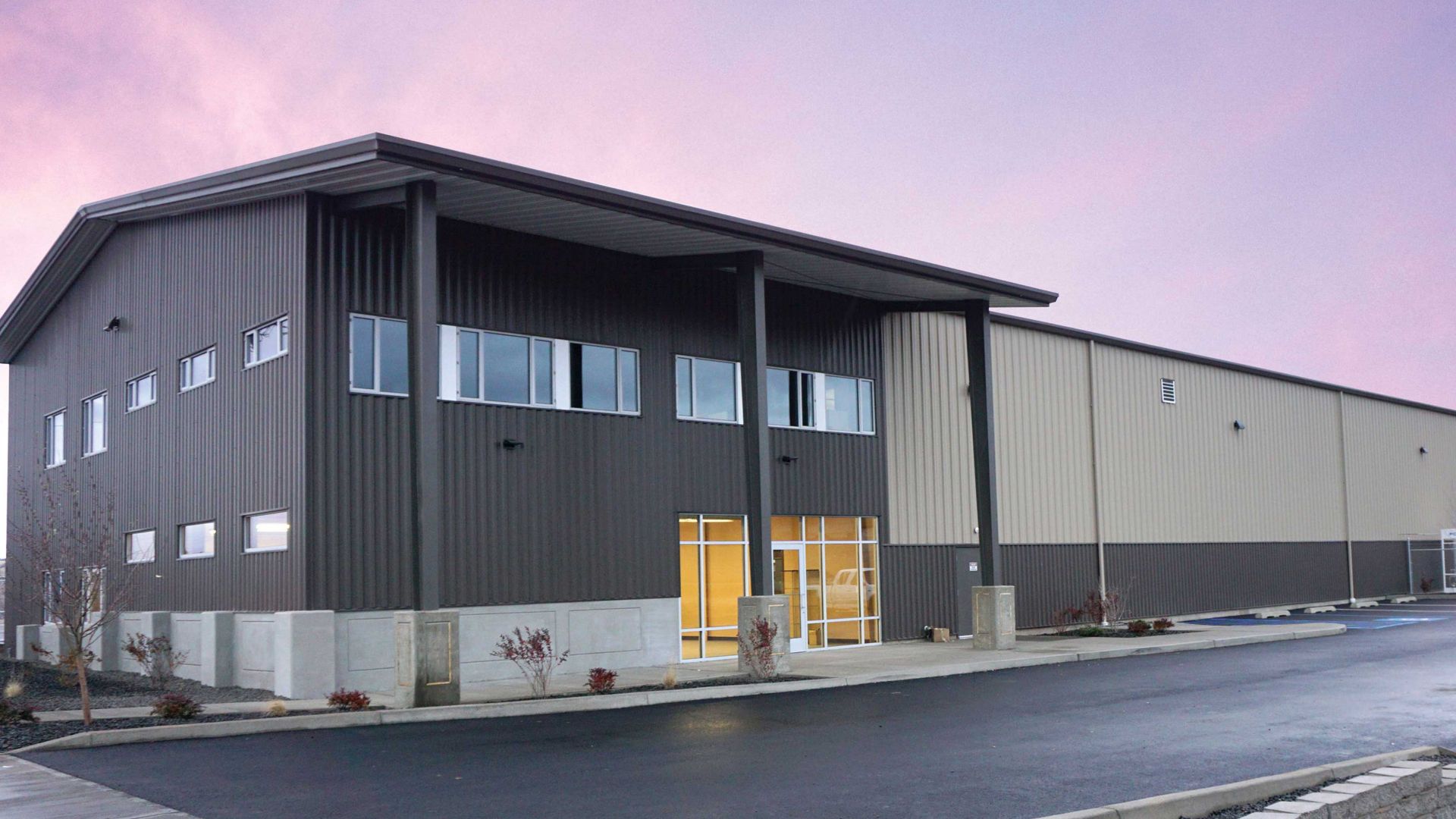 two story metal building with glass entry way with dramatic sky in background.