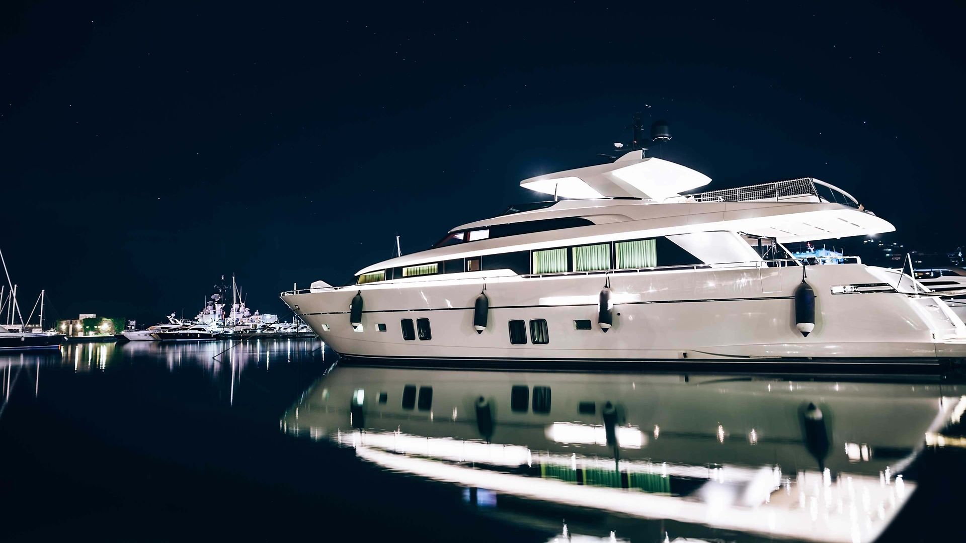 Luxury yachts in La Spezia harbor at night with reflection in water. Italy