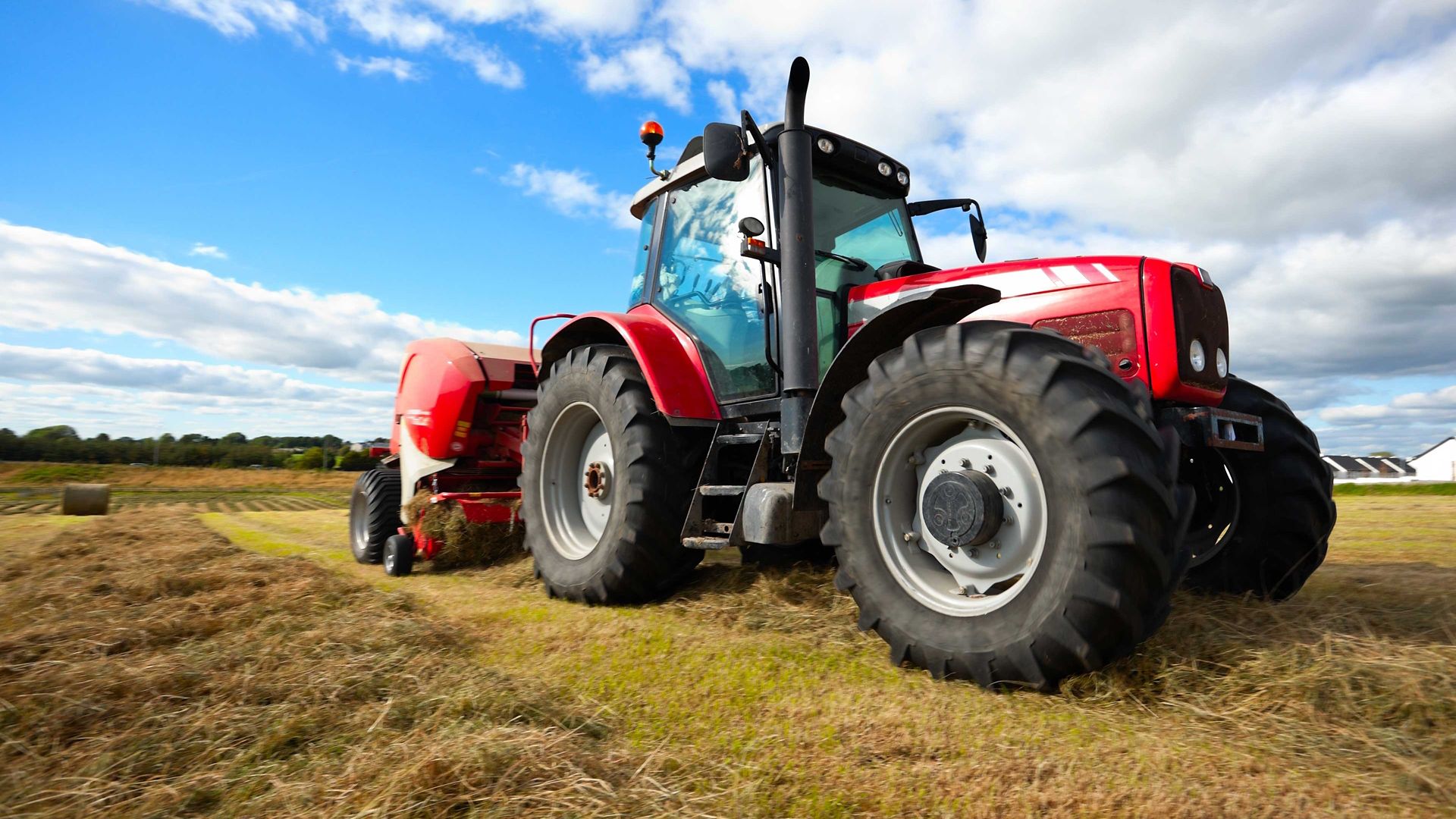 farm tractor in field with clouds in background; agricultural vehicle in farm field