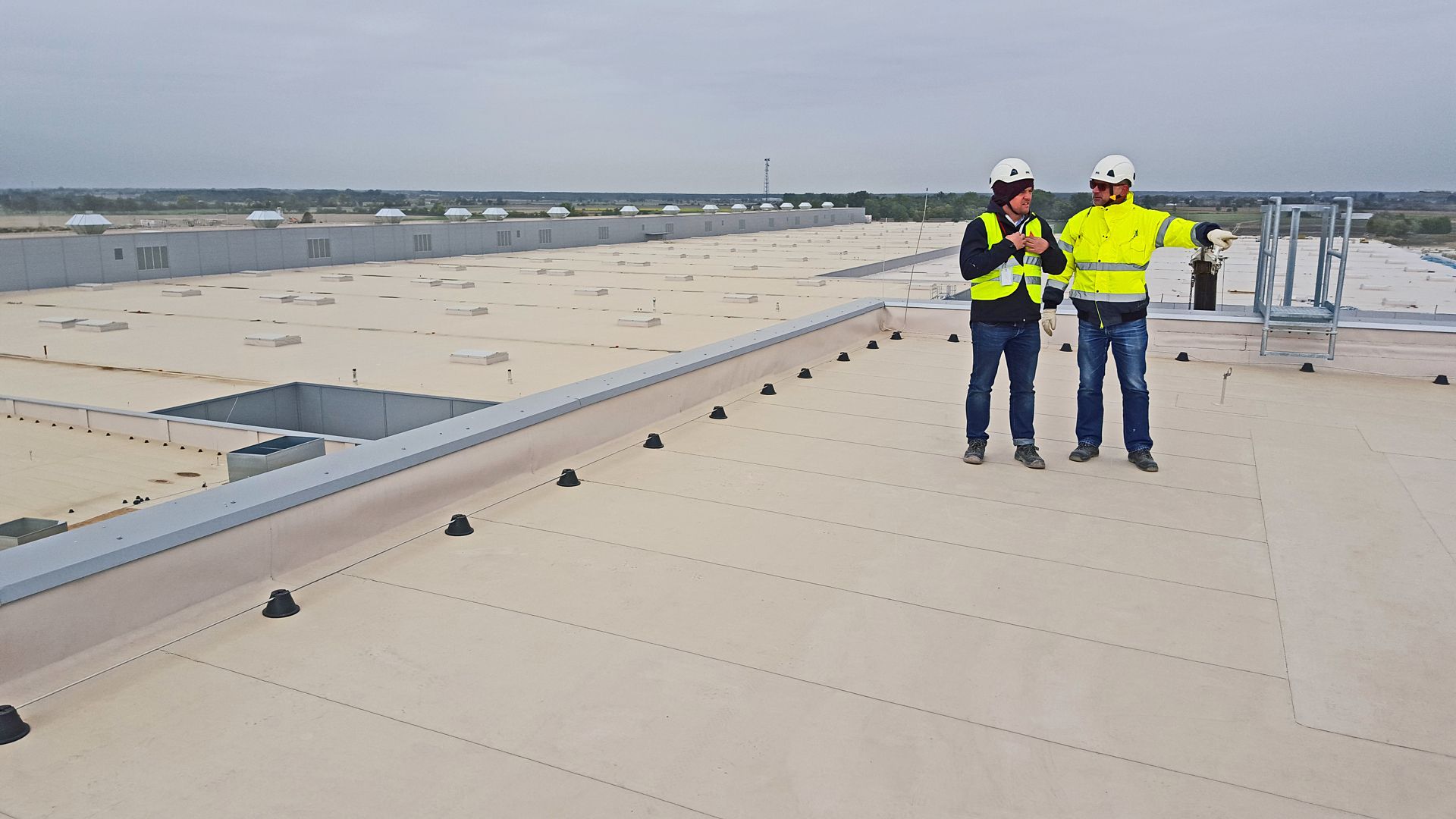 Two construction workers standing on Sarnafil waterproofing membrane on roof of Volkswagen Plant