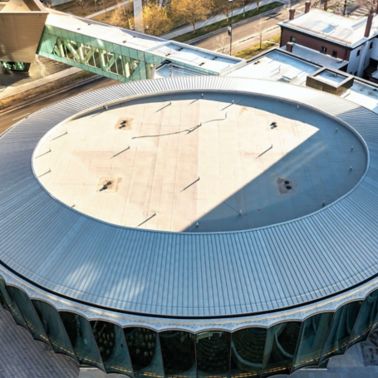 Aerial view of a section of the Denver Art Museum showing a white Sarnafil membrane on a circular roof with a ribbed roof outline