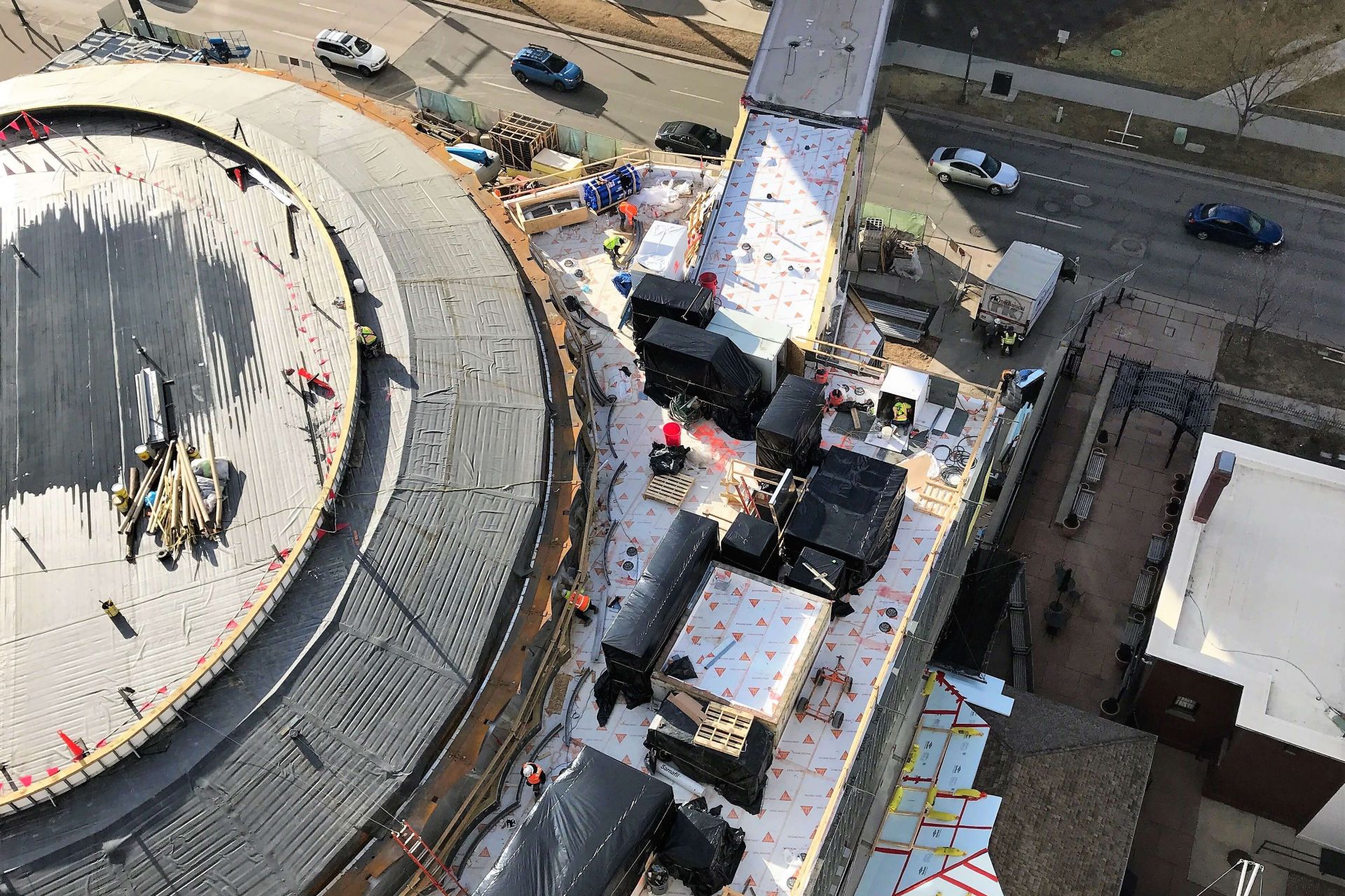 Aerial view of the Denver Art Museum while it is under construction. Workers can be seen laying down roofing membrane. 